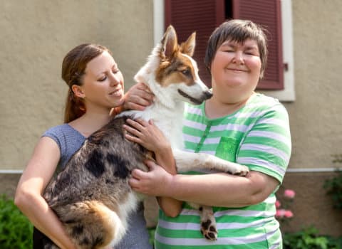a caregiver and a girl with dogs smiling